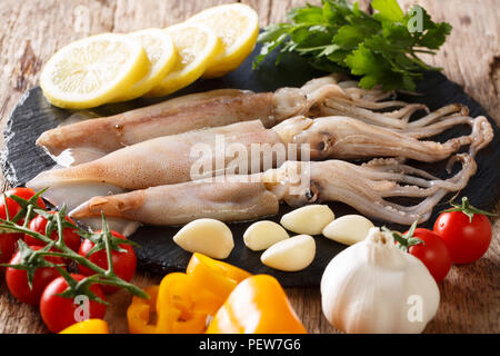 Frischen, rohen Tintenfisch mit Tentakeln closeup und pflanzlichen Zutaten auf den Tisch. Horizontale Stockfoto
