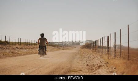 Rückansicht des Menschen reiten Motorrad auf einer Landstraße. Motorradfahrer Fahrten entlang einer Landstraße. Stockfoto