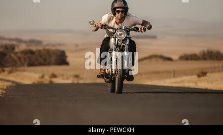 Porträt der jungen Mann, der ein Motorrad schnell auf der Autobahn. Männliche Fahrer nach vorne während der Fahrt sein Motorrad. Stockfoto
