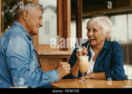 Portrait von fröhlichen senior Paar am Tisch sitzen im Cafe. Gerne alte Paar sprechen und genießen einen kalten Kaffee im Cafe. Stockfoto