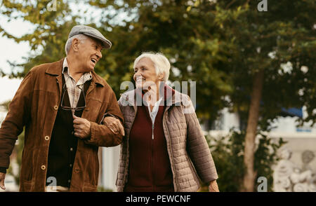 Portrait von Happy pensionierter Mann und Frau in warme Kleidung Wandern draußen auf der Straße. Liebevolle senior Paar genießen einen Spaziergang an einem Wintertag. Stockfoto