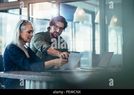 Der Mann und die Frau in einer Sitzung im Büro. Zwei Kollegen diskutieren über einen Bericht bei der Arbeit. Stockfoto