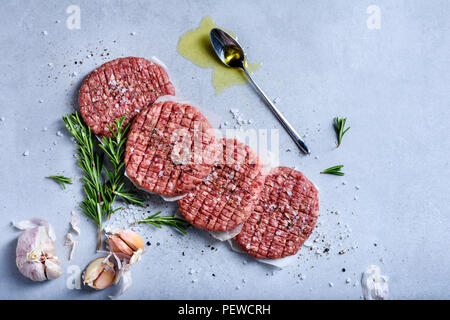 Hausgemachte rohes Hackfleisch Steak Burger mit Gewürzen und Kräutern, organische gesundes Essen kochen, Ansicht von oben, flach. Stockfoto