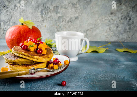 Herbstliches frühstück Idee, Kürbis Pfannkuchen, mit Scheiben von Kürbis, Ahornsirup oder Honig, Moosbeere, auf einem blauen konkreten Hintergrund, Platz für Text Stockfoto