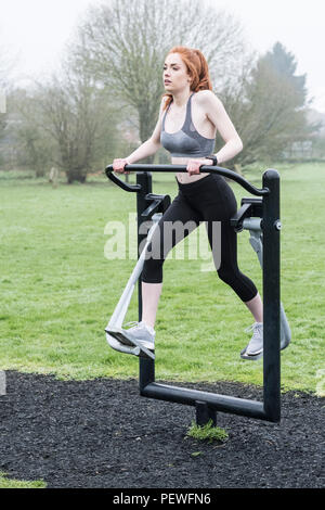 Junge Frau mit langen roten Haaren tragen Sportswear, mit Bewegung im Freien. Stockfoto