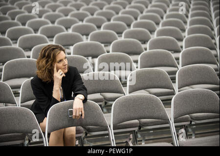Eine Geschäftsfrau allein in einem Raum voller Stühle vor einem Treffen in ein Konferenzzentrum. Stockfoto
