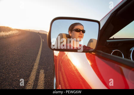 Eine junge Frau im Kaukasus Seite Spiegel ein Cabrio Sportwagen auf der Autobahn wieder. Stockfoto