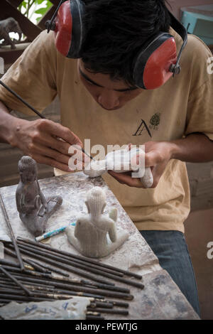 Ein kambodschanischer Bildhauer schnitzt sorgfältig einen Stein-Buddha in einem Kunstzentrum in Siem Reap, traditionelle Handwerkskunst und Kunst in Asien. Vertikale Ansicht Stockfoto