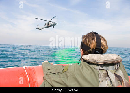 Oklahoma Army National Guard Chief Warrant Officer 2 McKayla Dembowski, ein Pilot mit Firma B, 1.BATAILLON, 140 Aviation Regiment, 40th Combat Aviation Brigade, Uhren von ihrem Schlauchboot als U.S. Navy MH-60S Seahawk Hubschrauber Hubschrauber Meer Combat Squadron 26 Ansätze während eines Personal Recovery Übung in den Arabischen Golf am 2. Diese Übung überprüft die Fähigkeit der American Service Members zusammen zu arbeiten, um die Besatzung eines abgestürzten Flugzeugs zu retten. (Foto: Staff Sgt. Ian M. Kummer, 40th Combat Aviation Brigade Public Affairs) Stockfoto