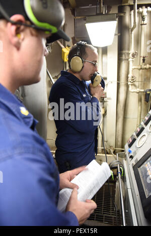 Feuerwehrmann Josef Günther, Mitglied der Hauptantrieb Division das Patrouillenboot der Polar Star, Relais eine Nachricht an Engineering, die der Cutter zentrale während Petty Officer 2nd class Keith Bryan, eine Maschinen Techniker in den Hauptantrieb Division der Polar Star, beim Engineering Unfall Übungen im Rossmeer beobachtet, in der Nähe der Antarktis, Feb 4, 2016. Die Bohrer simulieren Notfallsituationen in Motorräume für Ingenieure des Schiffes zu lernen und Ihre erste Antwort Techniken gelten. (U.S. Coast Guard Foto von Petty Officer 2. Klasse gewähren DeVuyst) Stockfoto