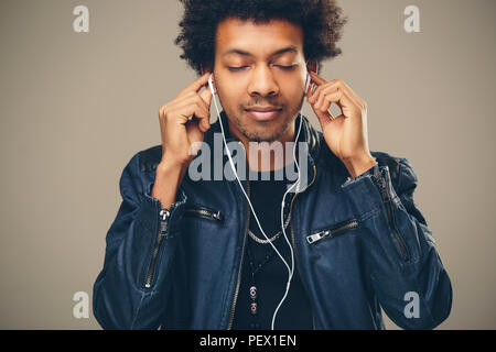 Happy afrikanischer Mann lächelnd das Hören von Musik über Kopfhörer. Weißer Hintergrund. Stockfoto