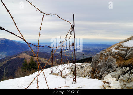 Veneto, Italien. Massiv des Monte Grappa, Mount Palon. Italienischer und französischer Graben, der durch Stacheldraht an der Front verteidigt wird, sind heute Teil des großen Freilichtmuseums des Great war River Piave im Hintergrund. - Veneto, Italien. Massiccio del Grappa, Monte Palon. Trincee Italo-Francesi difese dal filo spinato, subito sotto si vede il monte Tomba più volte conquistato e perduto dalle truppe austro-ungariche. In lontananza, nella pianura, Scorre il Piave. Restauri effettuati nell'ambito del progetto del museo all' aperto della grande Guerra. Stockfoto