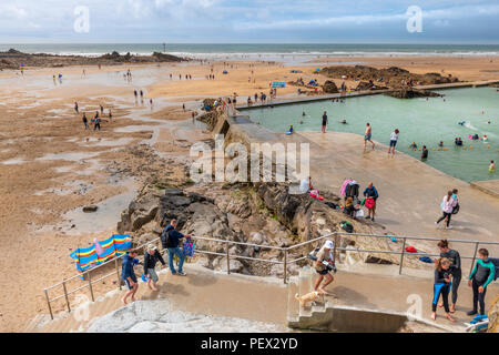 UK Wetter - An einem sonnigen Perioden mit zunehmender Cloud, der open air seapool an der Küste von Bude beweist bei Urlaubern beliebt, trotz t Stockfoto