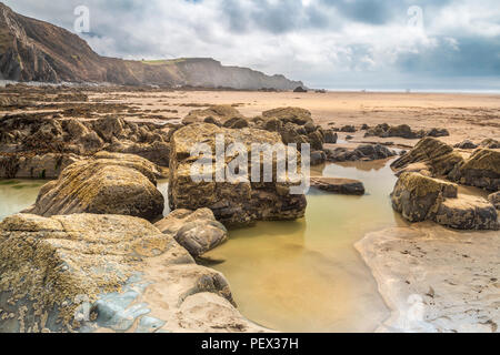 Eine der vielen Felsformationen ermöglicht eine tiefe Pool auf die weite offene Strand auf Sandymouth in North Cornwall zu bilden. Stockfoto