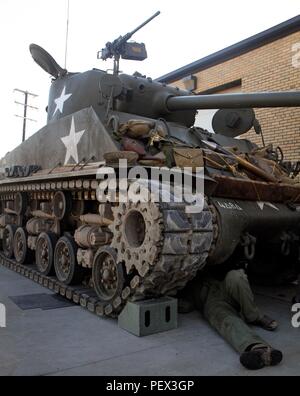 Ein Reenactor aus dem Zweiten Weltkrieg und ein Reparaturmann aus Segeltuch führt Reparaturen unter dem Bauch eines M4 Sherman-Panzers durch, um den Sitz des Schützen während einer Trainingsübung der Nationalgarde der Pennsylvania Army funktionsfähig zu machen. Der Re-Enactor unterstützt das Offiziersentwicklungsprogramm des 728th Combat Sustainment Support Battalion. Der Sherman-Panzer, angetrieben von einem Continental R975-Radialmotor und ausgestattet mit einer 75-mm-Hauptkanone, dient als historisches Lehrmittel, das Wartung, den Betrieb der Besatzung und die Einsatzbereitschaft gepanzerter Fahrzeuge demonstriert. Stockfoto