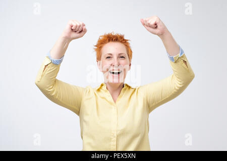 Happy kaukasische Frau mit roten Haaren frohlockt pumpen Fäuste ekstatisch feiert Erfolg. Ich habe getan, es Wow Konzept Stockfoto