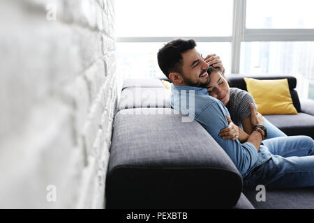Junges Paar, Umarmen und Küssen auf dem Sofa Stockfoto