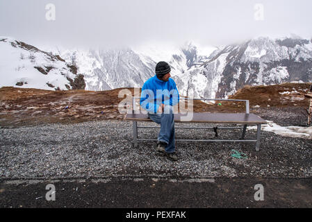 Georgischer Mann sitzt auf einer Beule hinter Bergblick. Georgische Militärstraße. Georgien. Stockfoto