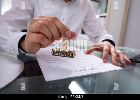 Der Geschäftsmann Hand Stanzen Genehmigt auf Vertrag Papier mit Stamper Stockfoto