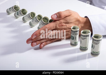 Hohe Betrachtungswinkel und einer Person anhalten, bis Banknoten auf dem Schreibtisch gerollt Stockfoto