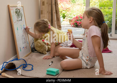 Junge zwei Jahre altes Mädchen sass bei fünf Jahre alten Schwester, Zeichnung mit Farbstift auf dem Whiteboard, künstlerische, Stockfoto