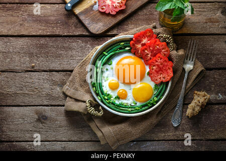 Sonnenseite Spiegelei in einer Kupfer Pfanne mit Tomaten und grünen Bohnen, kopieren. Stockfoto