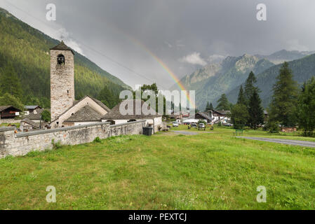 Berg mit Rainbow und charakteristische steinerne Kirche. Traditionelle alpine Village, Macugnaga, Piemont, Italien Stockfoto