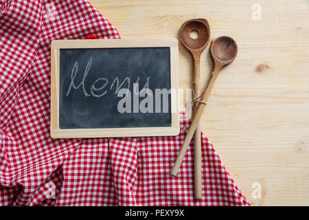 Menü Konzept. Tafel- und Küchengeräten auf rot Tischdecke, Holztisch, Platz für Text, Ansicht von oben Stockfoto