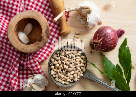 Gesundes Kochen. Black-eyed Beans, Kräutern und roten Tischdecke auf Holztisch, Ansicht von oben Stockfoto