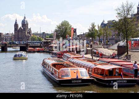 Zahlreiche touristische Boote auf dem Fluss IJ in Amsterdam, Niederlande Stockfoto