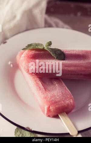 Heidelbeere Eis oder Eis am Stiel mit grüner Minze auf weißen Kunst Platte. Rustikal farbe Stil. Gefrorenes Obst Saft im Vintage Style. Ansicht von oben Foto. Stockfoto