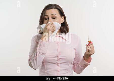 Kranke Frau mit einem Taschentuch und Nasenspray. Stockfoto