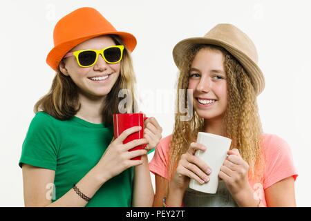 Mädchen Freundinnen 12-14 Jahre alt, auf einem weißen Hintergrund für Hüte, holding Cups. Stockfoto