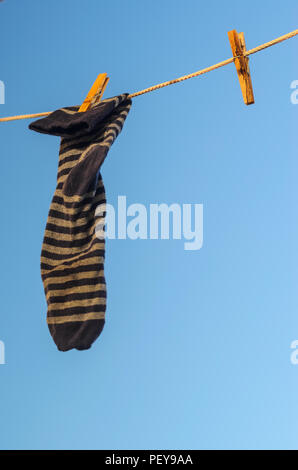 Gestreifte Socken hängen an einer Wäscheleine vor dem Hintergrund des blauen Himmels. Stockfoto