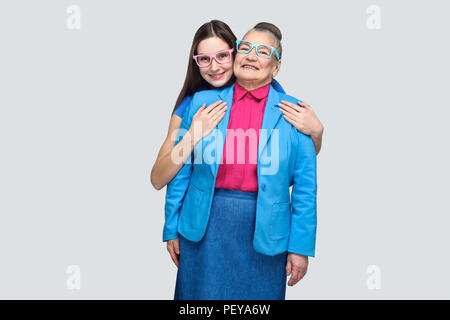 Zufrieden zufrieden Enkelin ihrer Großmutter umarmt und Kamera mit toothy Lächeln. Freundschaft oder Beziehung und gegenseitiges Verständnis. Stockfoto