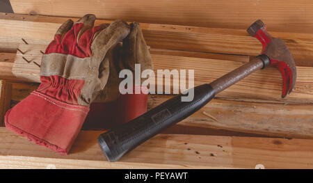 Alte rostige Hammer und Bau Handschuhe auf Holzbrett im Studio festgelegt Stockfoto