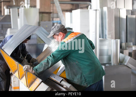 Belarus, Gomel, 25. April 2018. Fabrik für die Herstellung von Lüftungsrohren. Zwei Arbeiter Metall lüftung Rohre in der Werkstatt an der Faktor machen Stockfoto