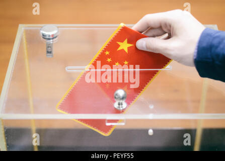 Mann einfügen Flagge von China in die Wahlurne, Abstimmungen und Wahlen in China. Stockfoto