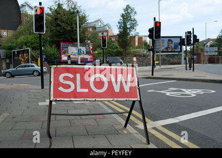 Temporäre Rot und Weiß langsam Zeichen an einem Signal gesteuert Kreuzung mit Baustellen in Kingston upon Thames, Surrey, England Stockfoto