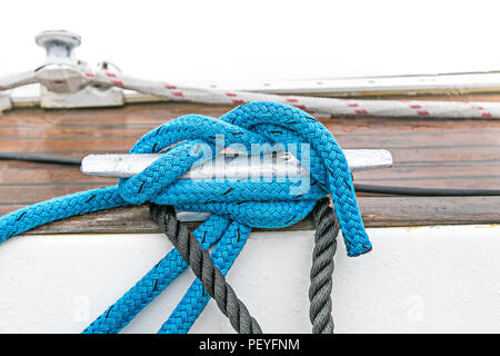 Blaue Linie ist um eine Yacht Klampe gewickelt und in einem Knoten gebunden. Stockfoto