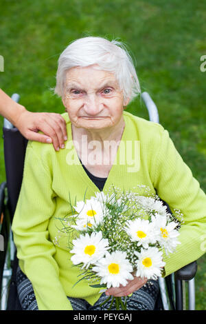 Ältere Frau an Demenz leiden Krankheit Blumen zum Geburtstag empfangen Stockfoto