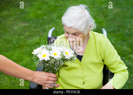 Ältere Frau an Demenz leiden Krankheit Blumen zum Geburtstag empfangen Stockfoto