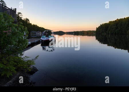 Ein bootshaus mit einem Wakeboard boot es geparkt auf See Joseph in der Morgendämmerung. Stockfoto