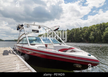Ein wakeboard Boot an einer hölzernen Dock in der muskokas an einem sonnigen Tag. Stockfoto