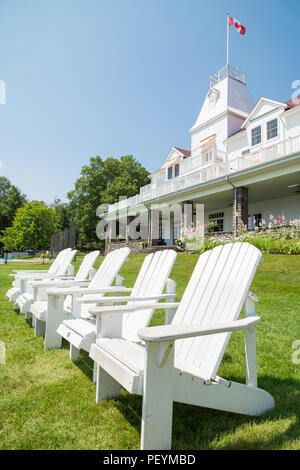 WINDERMERE, ON, Kanada - 21. JULI 2017: Eine Reihe von Muskoka Stühlen sitzen auf der Wiese vor dem historischen Windermere House am Lake Rosseau, Ontario. Stockfoto