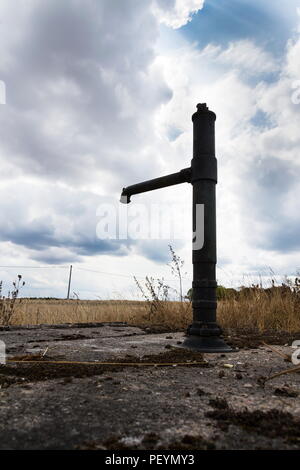 Alte Pumpe mit trockenem Boden, dramatische Wolkenhimmel, Wassermangel Stockfoto