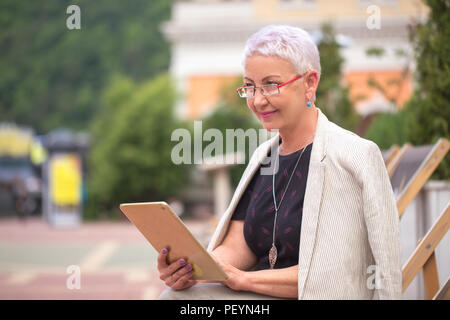 Nahaufnahme, Seite, Ansicht Foto von lächelnden Frau über ihre unternehmerischen Denkens in der Straße Stockfoto