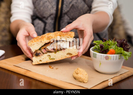 Ein Steak Sandwich auf Focaccia-brot mit einem Beilagensalat. Stockfoto