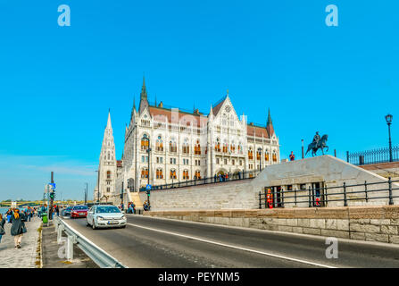 Touristen und Autos fahren die Waterfront Avenue entlang der Donau mit dem ungarischen Parlament in Budapest, Ungarn Stockfoto