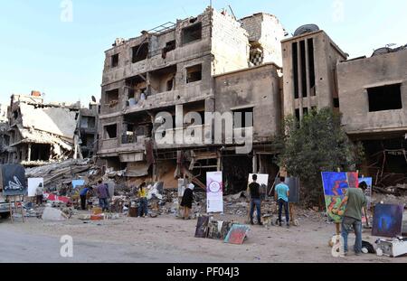 Damaskus, Syrien. 16 Aug, 2018. Syrische Künstler zeichnen Bilder inmitten der Trümmer und der Vernichtung der Yarmouk Camp, südlich von Damaskus, Syrien, am 12.08.16., 2018. Die Künstler haben Gemälde von Frauen, Kindern, Gebäude oder alles, was das Leben der Yarmouk Camp, die einst eine Heimat für die Palästinenser und Syrer südlich von Damaskus war hinzufügen könnten. Credit: Ammar Safarjalani/Xinhua/Alamy leben Nachrichten Stockfoto